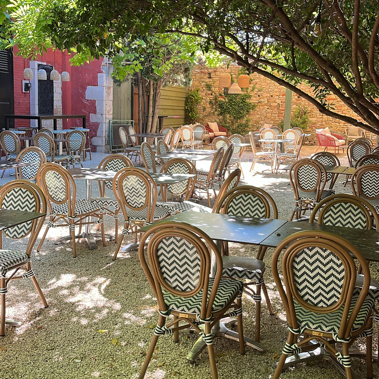 Terrasse ombragée du Ponte Loco avec chaises bistrot et mur de pierres sous les arbres